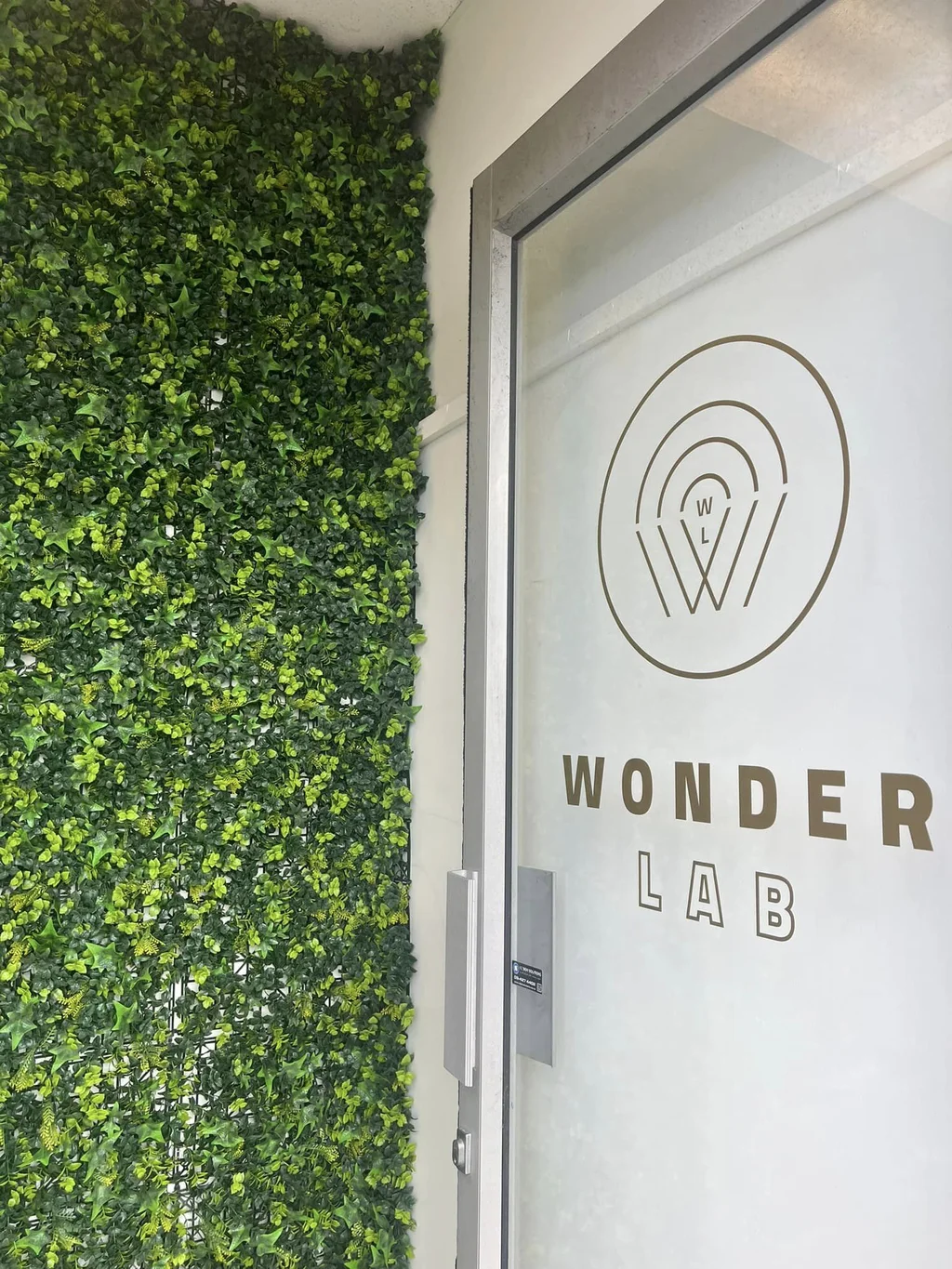 Wonder Lab's branded glass entrance beside a lush green living wall